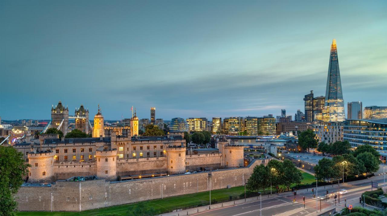 Tower Suites By Blue Orchid Лондон Екстериор снимка The photo shows a view of a historical site and modern skyline. In the foreground, there is a prominent historical building, likely a castle or fortress, featuring tall towers and a stone wall. This structure is set against a backdrop of contemporary