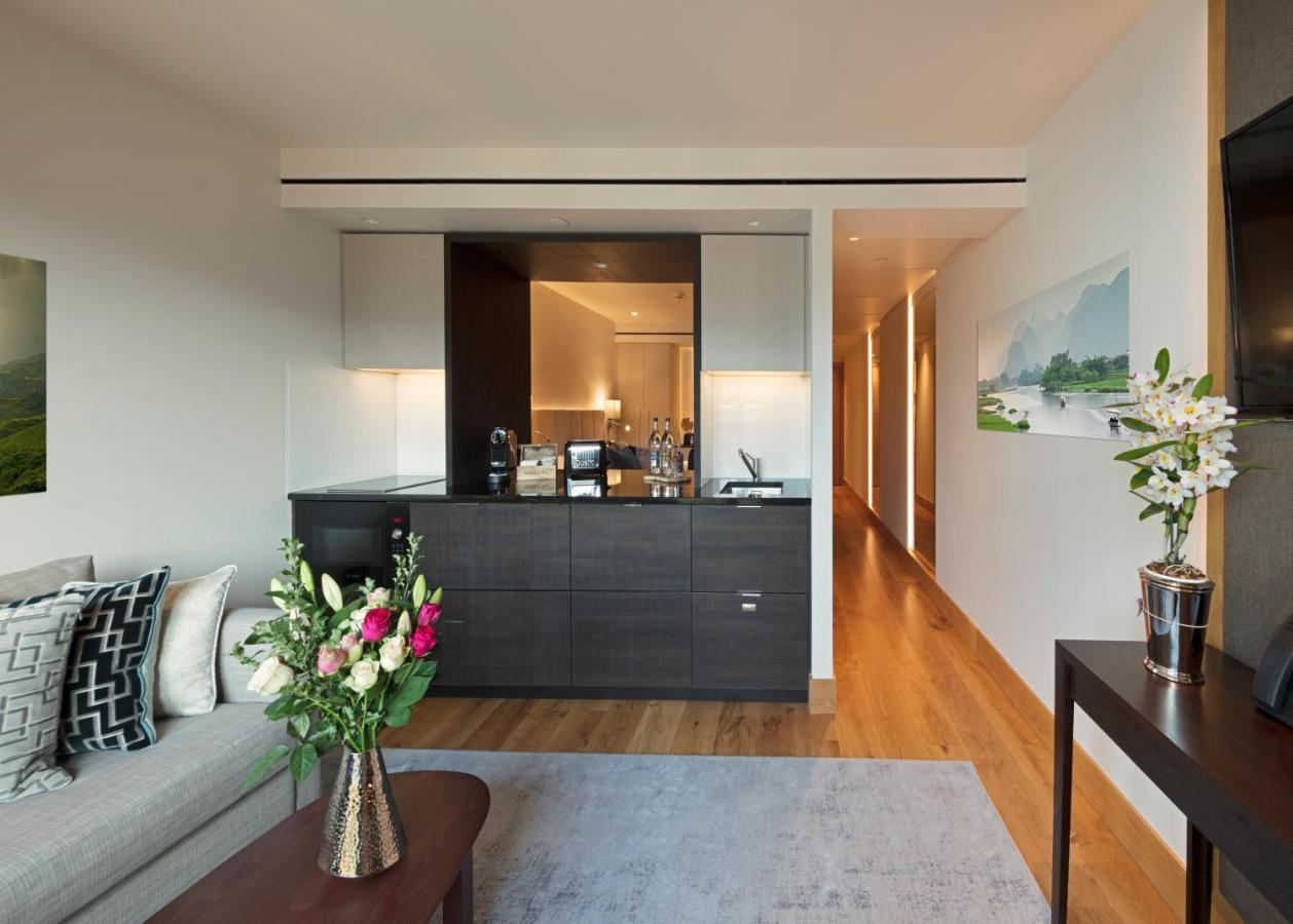 Tower Suites By Blue Orchid Лондон Екстериор снимка The photo showcases a modern and stylish interior space, likely a living area of a luxurious apartment or hotel suite. 

- **Bar Area**: There is a sleek bar counter that features a variety of bottles and glassware, suggesting a well-equipped space f