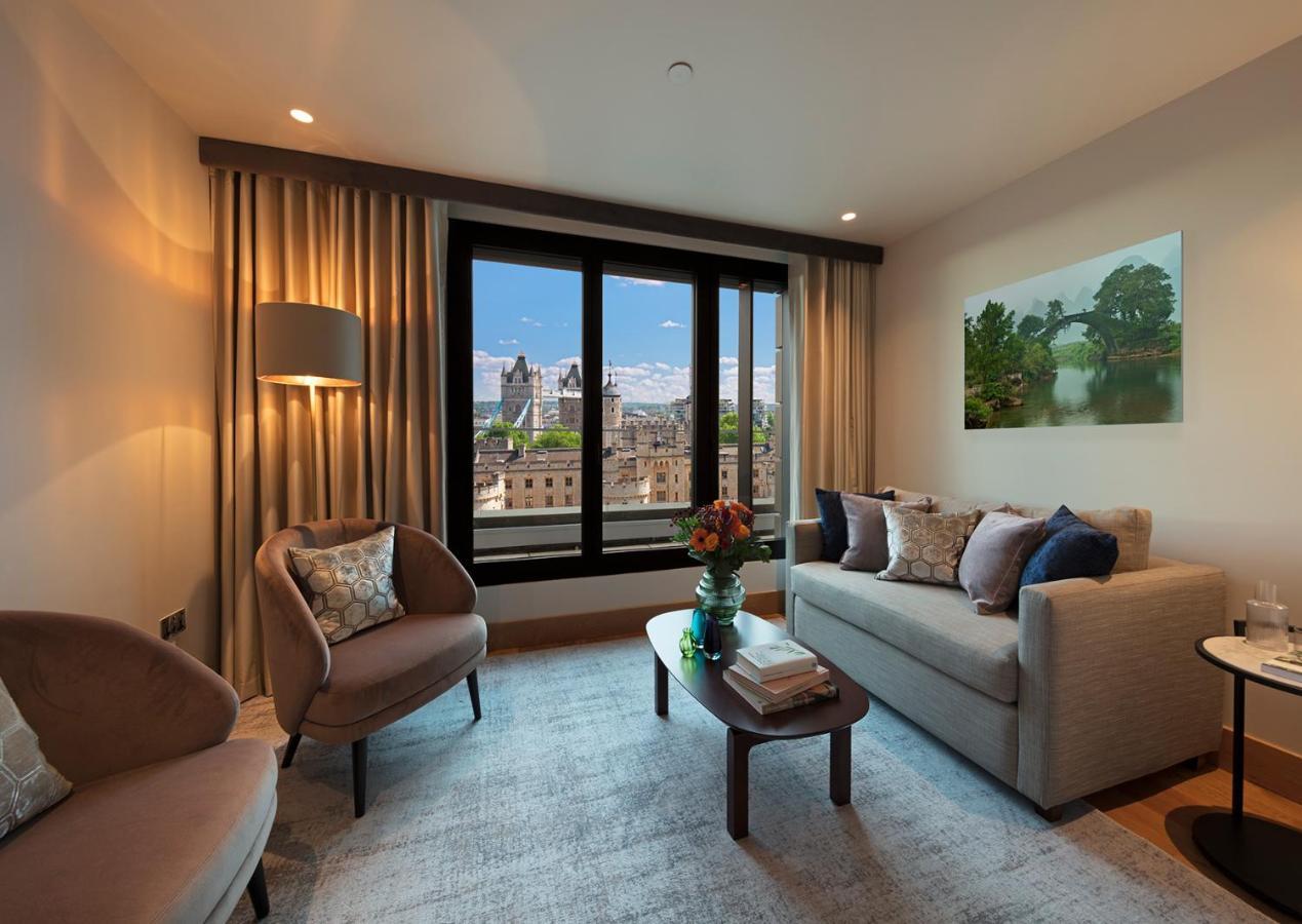 Tower Suites By Blue Orchid Лондон Екстериор снимка The photo depicts a modern living room with a contemporary design. It features two stylish, circular chairs and a comfortable sofa adorned with various decorative pillows. A small coffee table is positioned in front of the sofa, topped with books and
