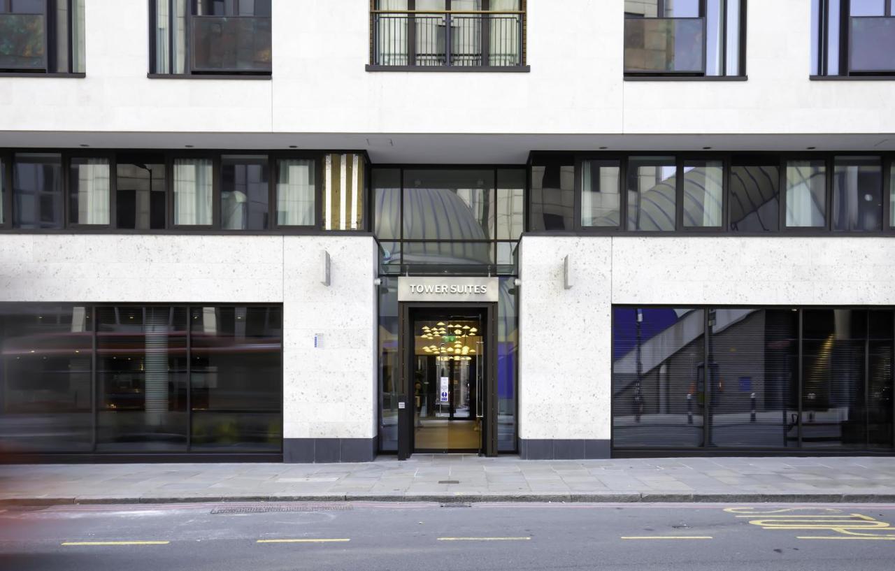 Tower Suites By Blue Orchid Лондон Екстериор снимка The image shows the entrance of a modern building, characterized by its minimalist architectural design. The facade features a combination of large glass windows and smooth stone surfaces. The entrance is framed by glass doors, flanked by stylish lig