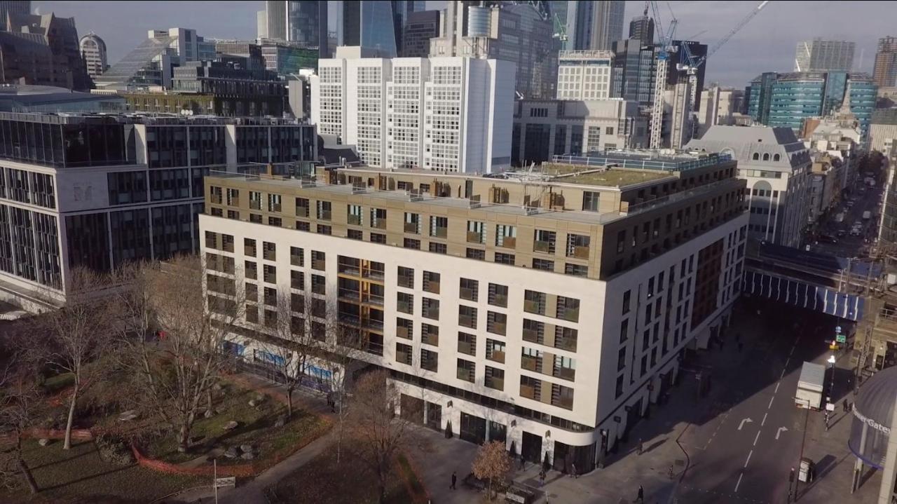 Tower Suites By Blue Orchid Лондон Екстериор снимка The photo shows a large, modern building with a combination of white and light-colored facades. The structure has multiple floors and features a series of square windows, providing a contemporary architectural style. Surrounding the building, there a
