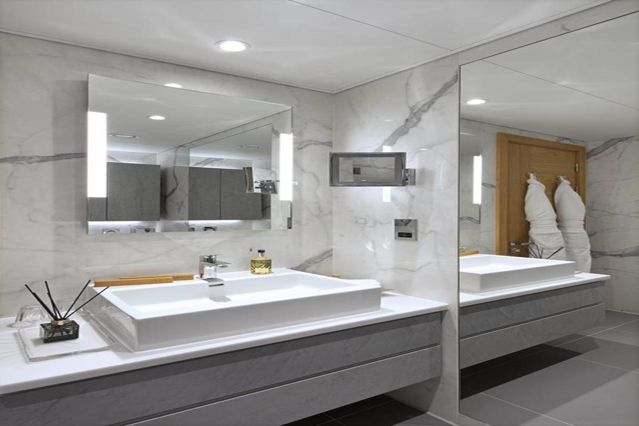Tower Suites By Blue Orchid Лондон Екстериор снимка The photo shows a modern bathroom featuring a sleek design. 

- **Vanity Area**: There is a rectangular sink set into a white countertop, paired with a minimalist faucet. 
- **Mirrors**: Above the sink, there is a large mirror that reflects the entir